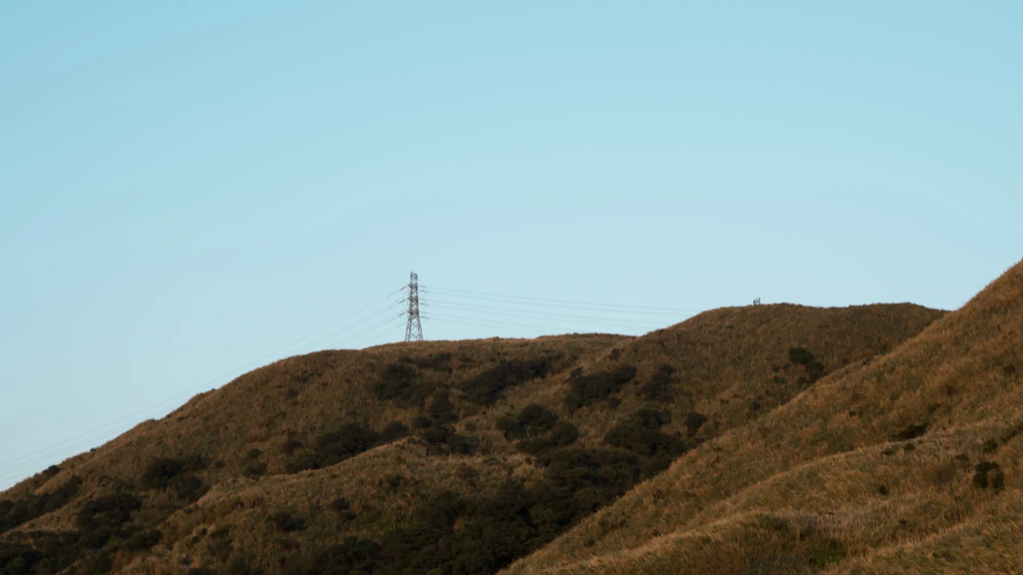 An image showing a transmission tower in a mountaineous region
